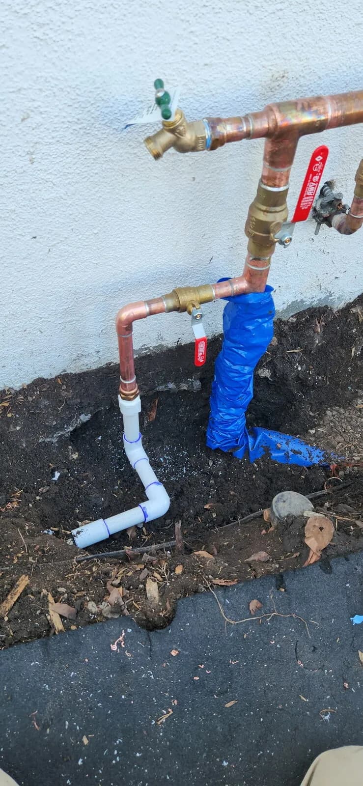 Exterior copper and PVC stub-ups with brass ball valves and hose bib in a residential trench