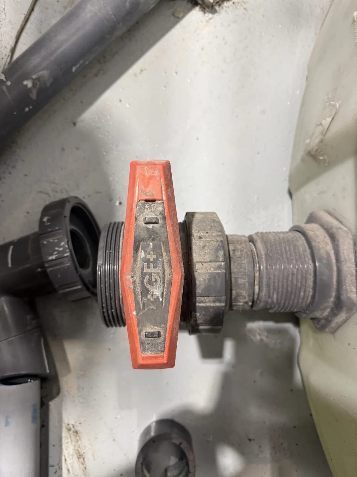Industrial grey PVC ball valve with red Georg Fischer handle connected to a plastic tank