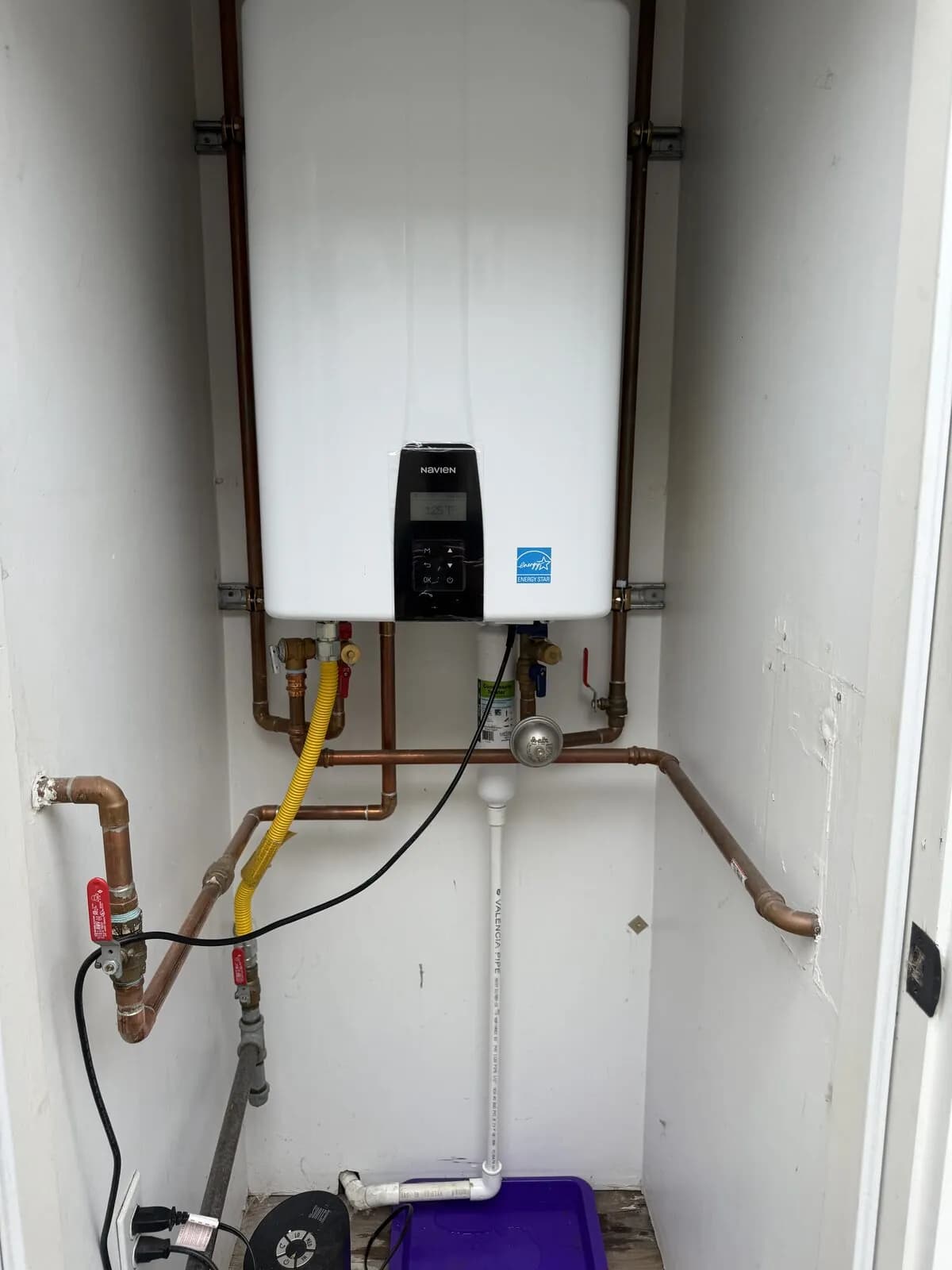 Navien Energy Star tankless water heater in a utility closet with copper valves and yellow gas line