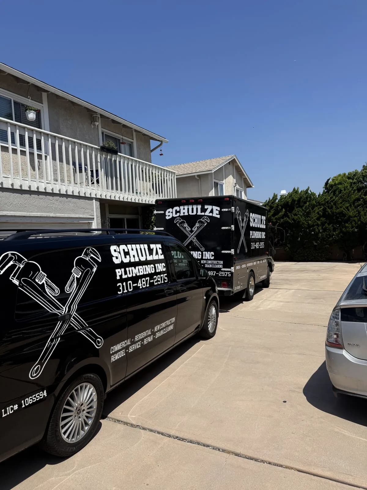 Schulze Plumbing Inc. service van and box truck parked at a residential job with company lettering
