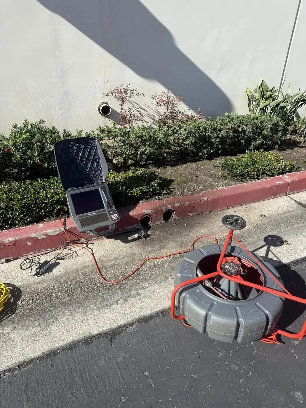 Sewer camera monitor and orange push-cable reel set up for a drain line inspection outdoors